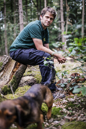 Ein Mann sitzt auf einem Baumstamm im Wald