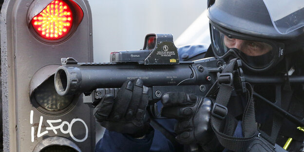 Ein Polizist zielt mit einem Gummigeschossgewehr