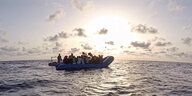 Seenotretter vom Rettungsschiff „Alan Kurdi“ die zu einem Schlauchboot voller Flüchtlinge schauen.