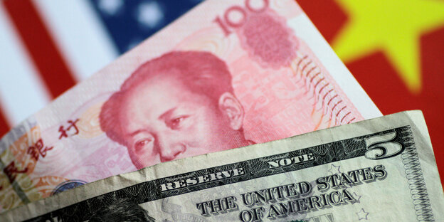 US-Dollar-Noten, dahinter ein Yuan Geldschein mit dem Gesicht von Mao