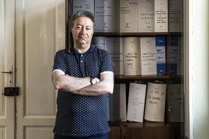 Ein Mann steht vor einem Regal mit Akten Ein Mann steht vor einem Regal mit Akten