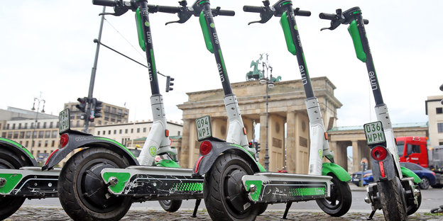 Vier E-Roller des Unternehmens Lime parken vor dem Brandenburger Tor