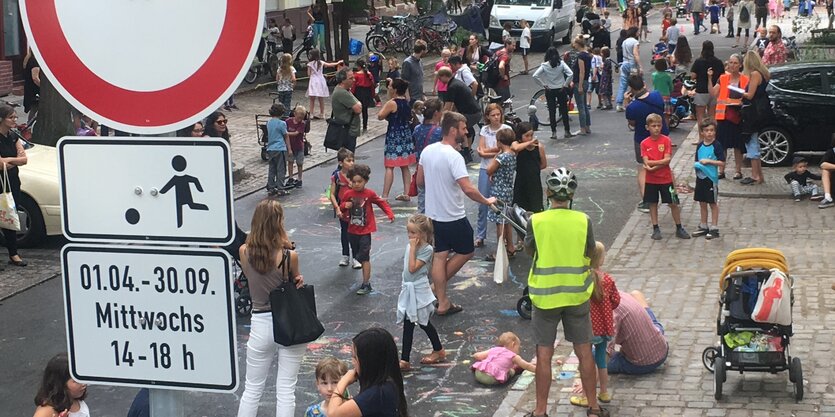 Kinder spielen auf der Straße, im Vordergrund ist ein Schild zu sehen