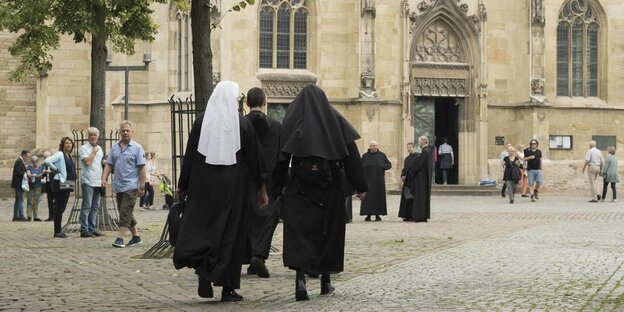 zwei Nonnen von hinten vor einer Kirche