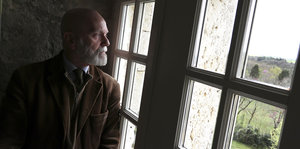 Renaud Camus, ein alter Mann, steht an einem Fenster