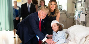Donald und Melania Trump lächeln neben einem Kind im Krankenhaus