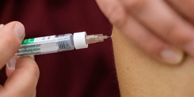 Impfen: Die Impfnadel steckt in einem Arm.