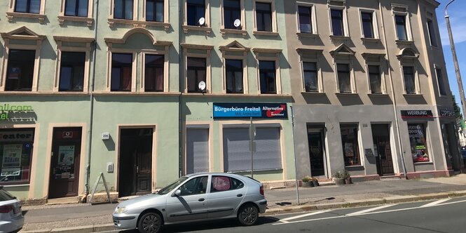 Eine Häuserfront mit einem AfD-Büro, dessen Rollläden verschlossen sind