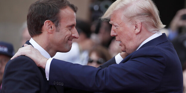 Emmanuel Macron und Donald Trump stehen sich gegenüber und lächeln sich an