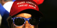 Ein Trump-Unterstützer trägt eine Cap mit der Aufschrift "Make America Great again". Er trägt außerdem eine Sonnenbrille, deren Rahmendie Farben der US-Fahne hat.