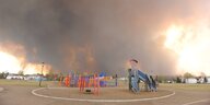 Ein Spielplatz in der Provinz Alberta. Hinter Klettergerüst und Rutsche tobt ein Feuer. Dicke Rauchschwaden liegen in der Luft.