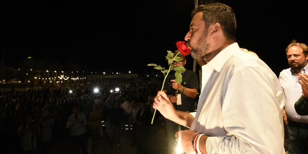 Italiens Innenminister Matteo Salvini steht mit einer roten Rose auf der Bühne.