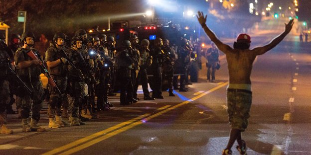 Schwer bewaffnete US-Polizisten stehen einem schwarzen Demonstranten gegenüber Schwer bewaffnete US-Polizisten stehen einem schwarzen Demonstranten gegenüber