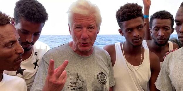 Richard Gere zusammen mit einer Gruppe von geretteten Flüchtlingen an Bord der Open Arms Richard Gere zusammen mit einer Gruppe von geretteten Flüchtlingen an Bord der Open Arms