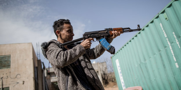 Ein Kämpfer der Regierung von Lybien hält ein Gewehr in der Hand und zielt.