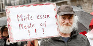 Ein Demonstrant hält ein Schild mit der Aufschrift "Miete essen Rente auf !!!".