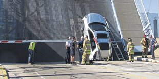 Feuerwehrleute stehen um ein Auto herum, das an einer Wand steht