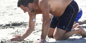 Matteo Salvini kniet mit nacktem Oberkörper und buddelt im Sand