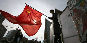 Ein Mann hält eine Sowjetfahne am Potsdamer Platz