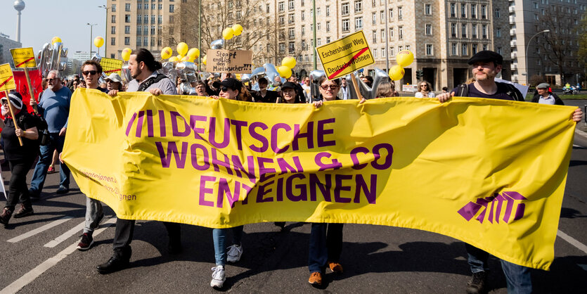 Mietenwahnsinn in Berlin: Menschen protestieren gegen steigenden Mieten und halten ein Banner des Volksbegehren Deutsche Wohnen & Co. Enteignen