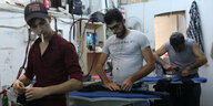 Drei Männer, syrische Geflüchtete, arbeiten in einer Textilfabrik