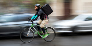 Ein Fahrradkurier fährt auf einem grünen Fahrrad