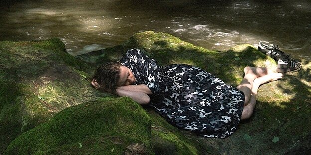 Eine Frau schläft auf einem Stein