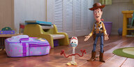 Eine animierte Plastikgabelfigur und ein ebenfalls animierter Spielzeugcowboy stehen in einer Wohnzimmerumgebung.