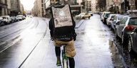 Ein Deliveroo-Fahrer fährt auf einem Fahrrad bei Regen durch Berlin