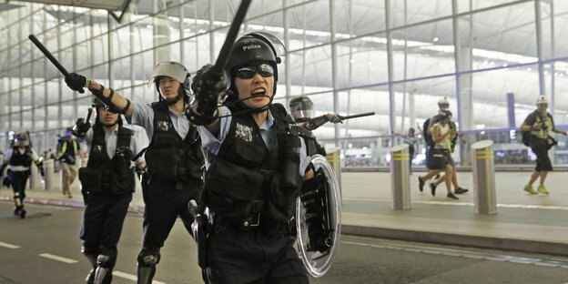 olizisten mit Schlagstöcken schreien Demonstranten im Hongkonger Flughafen an