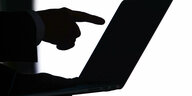 Ein Mensch hat einen Laptop auf dem Schoß und zeigt mit dem Zeigefinger auf den Bildschirm.