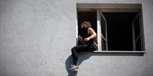 Hausbesetzerin sitzt auf einem Fensterbrett