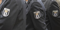 Die Schultern von drei Polizist*innen in Uniform, mit Abzeichen drauf