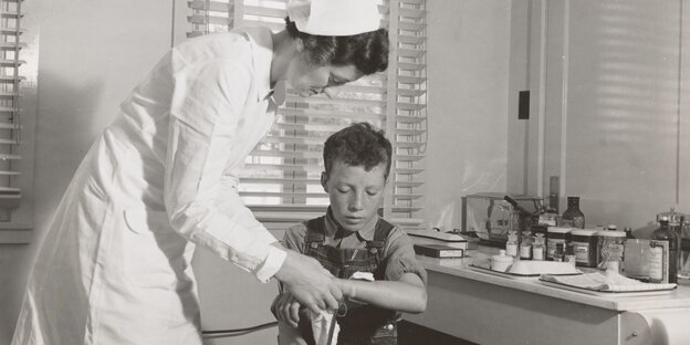 Pflegekammer gab es nicht: Schwarz-Weiß-Foto einer Krankenschwester mit kleinem Jungen