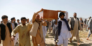 Männer tragen eines der Opfer des Anschlages auf eine Hochzeit zu Grabe