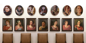 Über einer Reihe von Stühlen hängen die Porträts römischer Kaiser. Darüber Medaillons mit Filmheldinnen, die alle eine Waffe in der Hand haben.