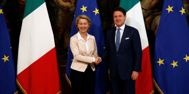 Premier Giuseppe Conte und Ursula von der Leyen geben sich vor Euopa- und Italien-Flaggen die Hand