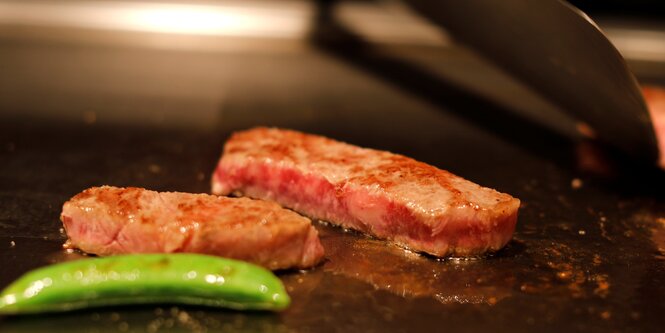 Zwei Steaktstücke in einer Pfanne mit einem Stück Gemüse