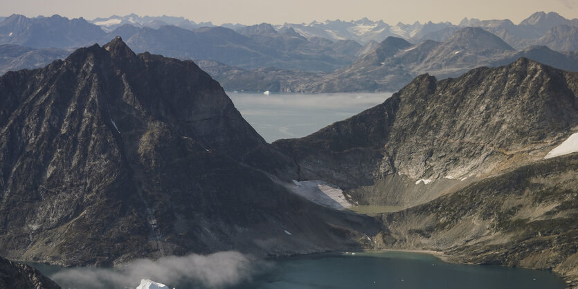 Eisberge treiben zwischen schneefreien Bergen - wir sehen ein Bergpanorama in Pastelltönen