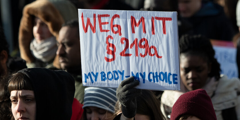 Menschen halten ein Schild mit "weg mit 219a" in die Luft