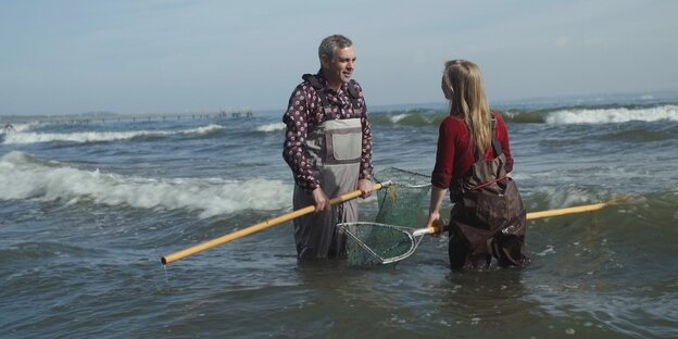 Zwei Menschen stehen mit einem Netz im Meer