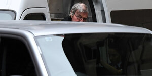 Ein Mann, George Pell, hinter einem auto