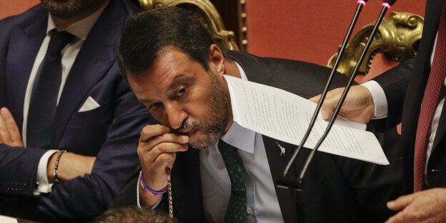 Matteo Salvini, im Parlament sitzend, küsst einen Rosenkranz