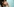Eine Frau im Profil steht vor türkiser Wand und hat gerade den Lippenstift abgesetzt