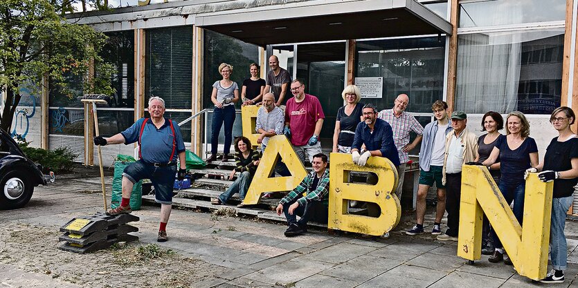 Freiwillige mit Arbeitshandschuhen stehen vor dem Billen-Pavillon.