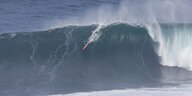 ein Frau surft eine riesige Welle
