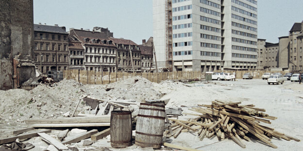 Die Farbaufnahme zeigt eine Brache voller Gerümpel auf der Berliner Fischerinsel. Im Hintergrund Altbauten und eine moderne Scheibe.