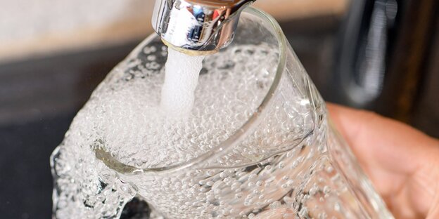 Wasser läuft aus einem Wasserhahn in ein Glas