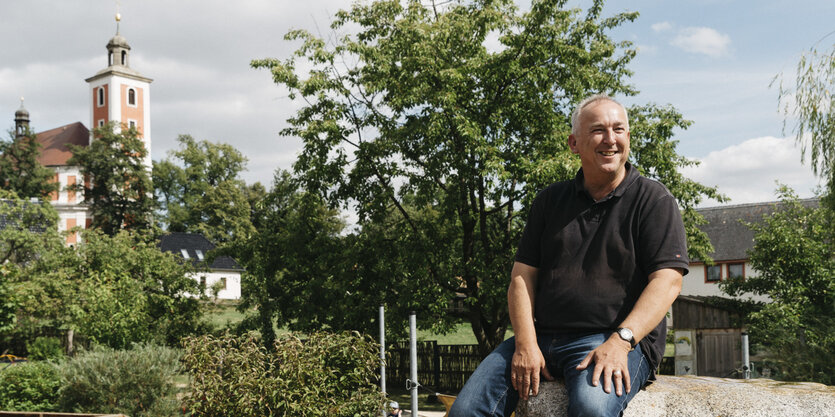 Mann auf Steinskulpur, Kirche im Hintergrund