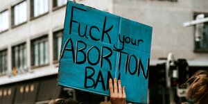 Ein blaues Pappschild auf dem steht: Fuck your Abortion Ban